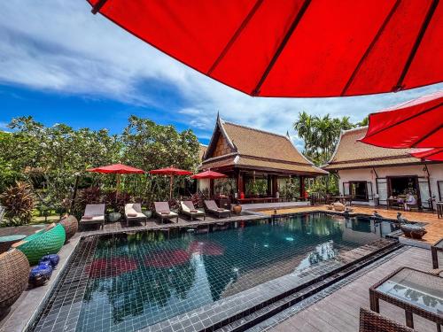 an outdoor swimming pool with chairs and an umbrella at Baan Thai Lanta Resort in Ko Lanta