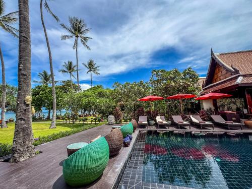 a swimming pool with chairs and umbrellas next to a resort at Baan Thai Lanta Resort in Ko Lanta