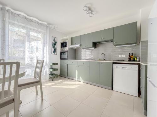 une cuisine avec des armoires vertes, une table et des chaises dans l'établissement T3 lumineux avec jardin, parking et piscine, à Puget-sur Argens