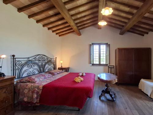a bedroom with a bed with a red blanket and a table at IL CASALE DEGLI ULIVI- Splendido casale panoramico con piscina a 30 min da Roma GRA in Calvi dellʼ Umbria