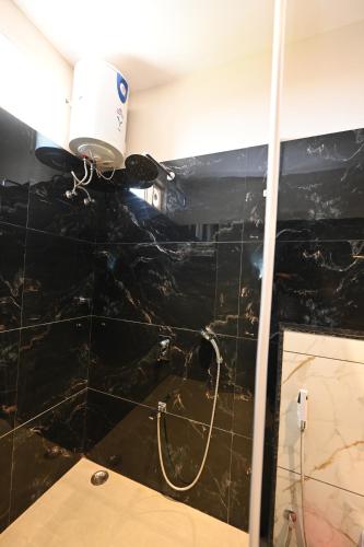 a shower in a bathroom with a black tiled wall at THE GANGA RESORT in Bikaner