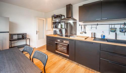 una cocina con armarios negros y una mesa con sillas en Le Ptit Stop, en Chalon-sur-Saône