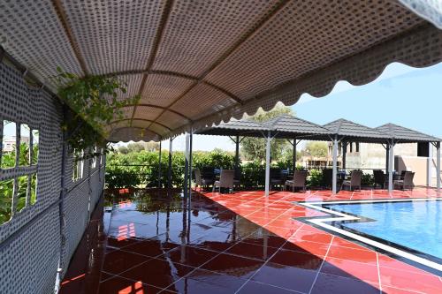 a swimming pool with tables and umbrellas next to a building at THE GANGA RESORT in Bikaner