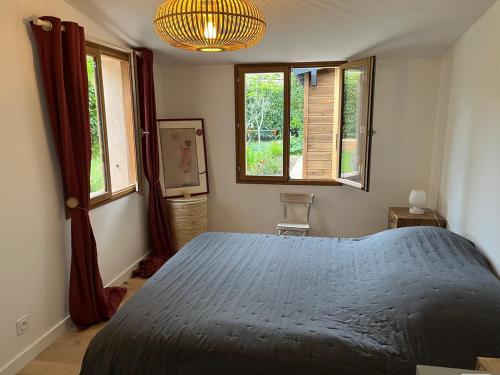 une chambre avec un lit bleu et deux fenêtres dans l'établissement Jolie maison de 95 m2 avec jardin proche Luberon, à Le Puy-Sainte-Réparade