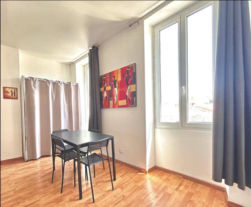 une table et des chaises dans une pièce avec une fenêtre dans l'établissement Appartement cosy non loin de la gare St Charles, à Marseille