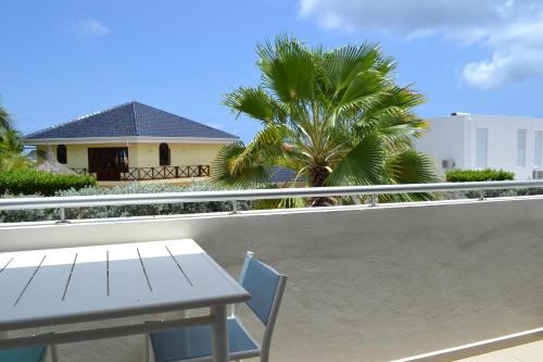 a table and chair on a balcony with a palm tree at Tropical villa Curoyal near the beach in Jan Thiel
