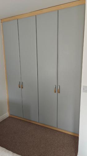 a row of four white cabinets in a room at Entire Cozy home 5 mins from Dublin Airport in Swords
