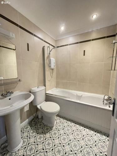 a bathroom with a toilet and a tub and a sink at Entire Cozy home 5 mins from Dublin Airport in Swords