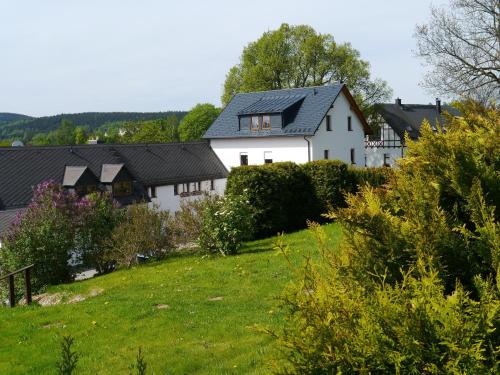 a white house with a black roof on a green field at Fewo Siebert in Bad Brambach