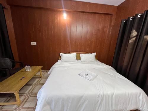 een groot bed in een kamer met een houten muur bij Bir Hotel by Aaroh in Bir