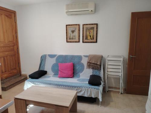 sala de estar con sofá azul y almohadas rosas en APARTAMENTO JAZMINERO, en Aguadulce