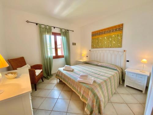 a bedroom with a bed and a chair and a table at Luxury apartment Ginepro sea view with common swimming pool just 50 mt from the beach in Golfo Aranci
