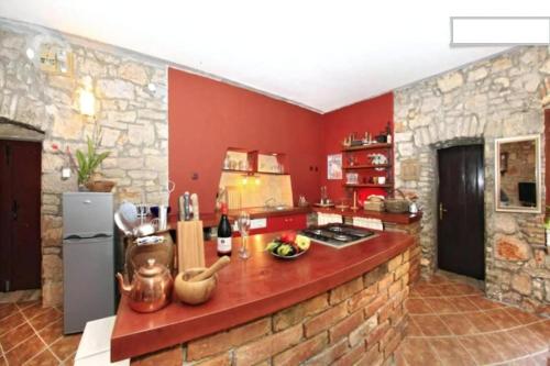 eine Küche mit roten Wänden und einer Steinmauer in der Unterkunft Ferienhaus für 3 Personen  2 Kinder ca 70 m in Preko, Dalmatien Inseln vor Zadar in Preko
