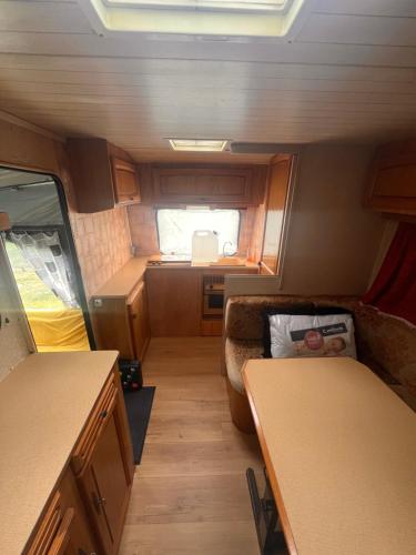 une vue intérieure d'une petite cuisine et salle à manger dans un camping-car dans l'établissement Caravane 4 couchage, à Coudeville-sur-Mer