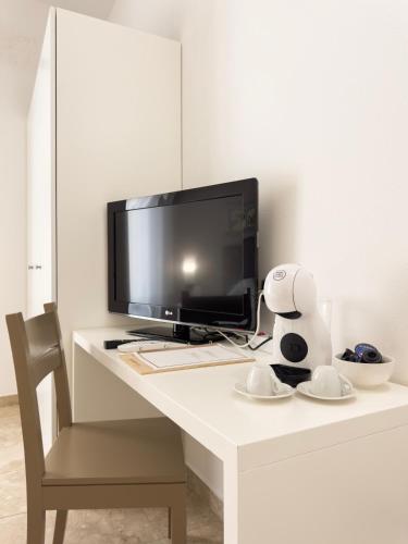 a computer monitor sitting on a white desk with a chair at San Domenico Residence by BADIA NUOVA in Trapani