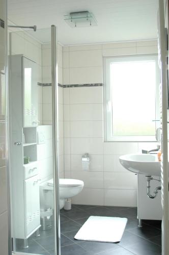 a white bathroom with a sink and a toilet at Ferienhaus Mit Indoorpool, Garten Und Partyraum in Geestland