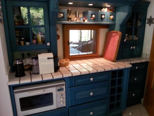 a kitchen with blue cabinets and a microwave at Ferienhaus Mit Einer Umwerfenden Panoramaaussicht in Glotzdorf