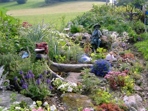 Kirchdorf im WaldLandhaus Wildfeuer的花园中种有鲜花,中间有雕像