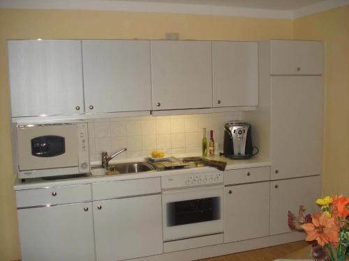 a kitchen with white cabinets and a sink and a microwave at Ferienwohnung Rachel Mit Herrlichem Ausblick in Rinchnach