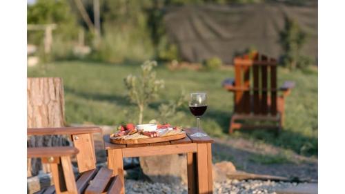 a glass of wine and a plate of food on a table at Rainforest Sunsets by Tiny Away in Kuranda