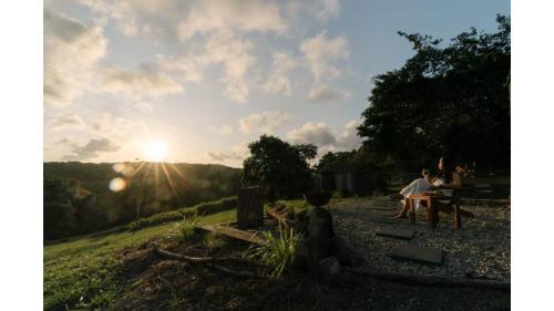 two people sitting at a table with the sun in the background at Rainforest Sunsets by Tiny Away in Kuranda