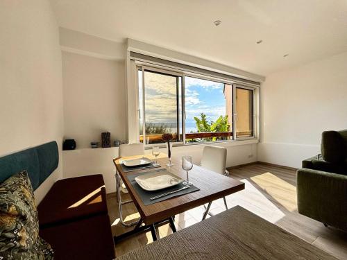 un salon avec une table et une grande fenêtre dans l'établissement Casamea - Studio vue mer, 2 min plage, Clim, à Ajaccio