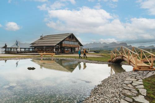 a bridge over a pond in front of a building at Rifugio Bec de Roces in Pallua