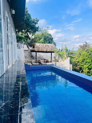 a swimming pool with a gazebo next to a building at Homestay Thác Liên Khương in Ðưc Trọng