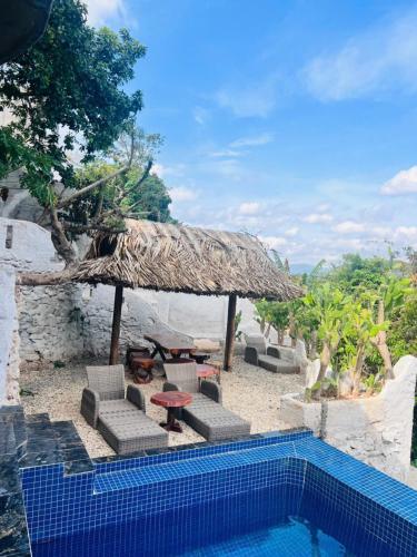 a resort with a swimming pool and a straw umbrella at Homestay Thác Liên Khương in Ðưc Trọng