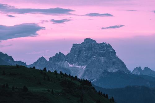 a mountain range with a pink sky and clouds at Rifugio Bec de Roces in Pallua