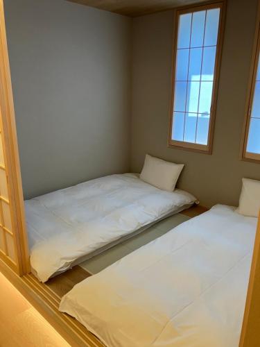 two beds in a room with two windows at MKG HOTEL Asakusa in Tokyo