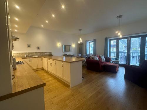 a large kitchen and living room with a couch at Tidemill House Apartment in Falmouth