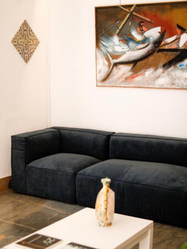 a living room with a blue couch and a painting at San Domenico Residence by BADIA NUOVA in Trapani