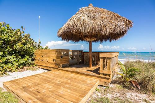 a wooden deck with a straw umbrella on the beach at Family Retreat At The Beach - Direct Oceanfront! in Indialantic