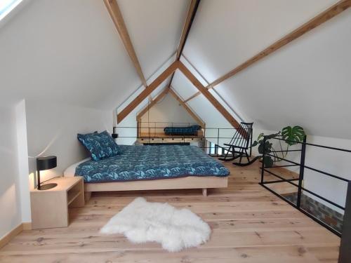 a bedroom with a bed and a wooden floor at Nachtegael Poorthuis. Een ruime, lichte woning in loft stijl. in Kluisbergen
