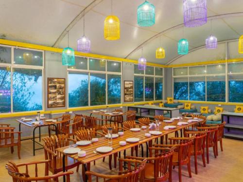 a large room with tables and chairs and windows at The Hosteller Munnar in Munnar