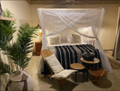a bedroom with a bed and a chair and a table at Toubacouta Lodges in Toubakouta