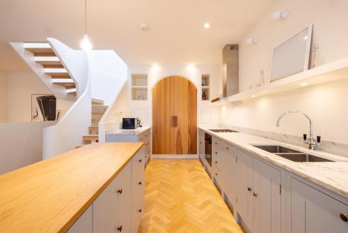 a kitchen with white cabinets and a staircase at Mews House South Ken in London