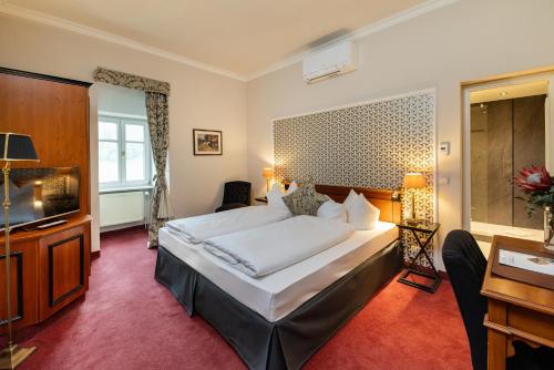 Una habitación de hotel con una cama y un televisor de pantalla plana. en Hotel Kaiserhof Eisenach, en Eisenach