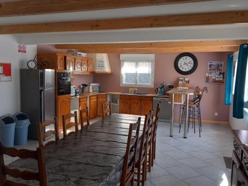 une cuisine avec une table et une horloge au mur dans l'établissement Gite Les sauvagines, à Pendé