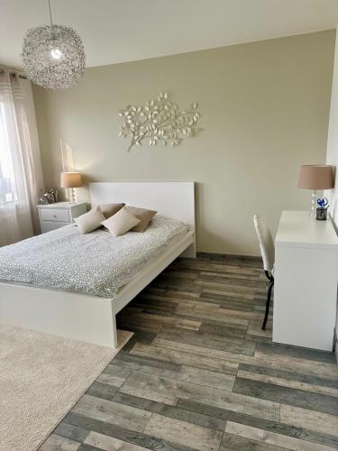 une chambre blanche avec un lit et un bureau dans l'établissement Apartment Reims, à Reims