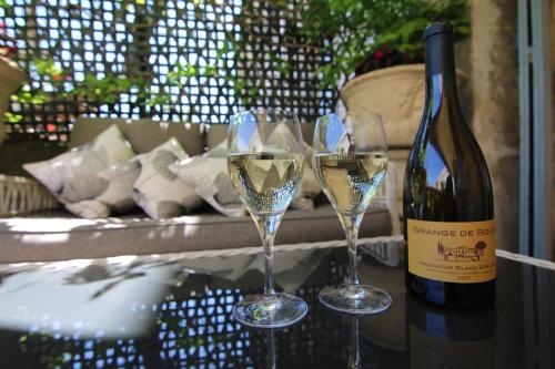 two glasses of white wine next to a bottle of wine at Cinq & Sept LGBT Resort for men in Roujan