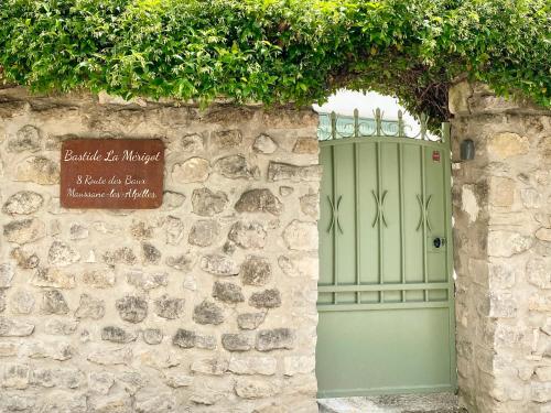 un mur de pierre avec une porte verte et un panneau dans l'établissement Bastide La Mérigot - Maussane-les-Alpilles, à Maussane-les-Alpilles