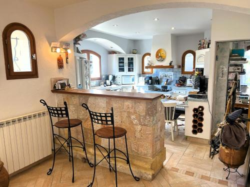 une cuisine avec deux tabourets de bar et un comptoir dans l'établissement Maison Familiale 3 chambres Cœur de la Nature, à Drap