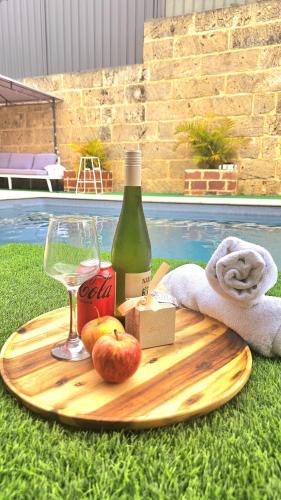 a bottle of wine and apples on a wooden cutting board at Joyful Living Guest House in Coogee