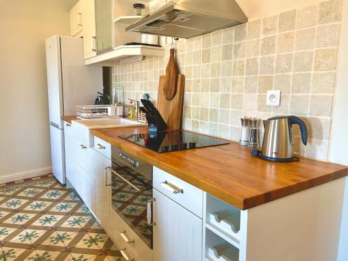 a kitchen with white cabinets and a wooden counter top at Cinq & Sept LGBT Resort for men in Roujan