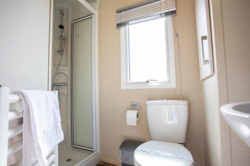 a bathroom with a toilet and a sink and a window at Barmouth Bay Holiday Park in Barmouth