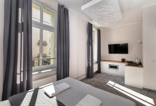 a white room with a bed and a television at SAVOY Mariacka Apartments in Katowice