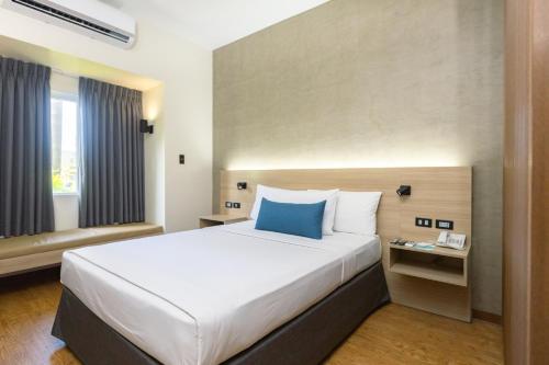 a bedroom with a large bed with a blue pillow at Microtel by Wyndham General Santos in General Santos
