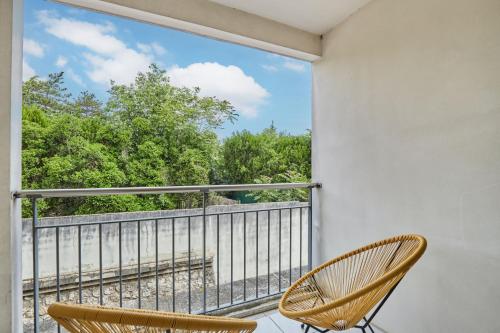 a balcony with two chairs and a large window at Appart Hotel Odalys City Aix en Provence Le Clos de la Chartreuse in Aix-en-Provence